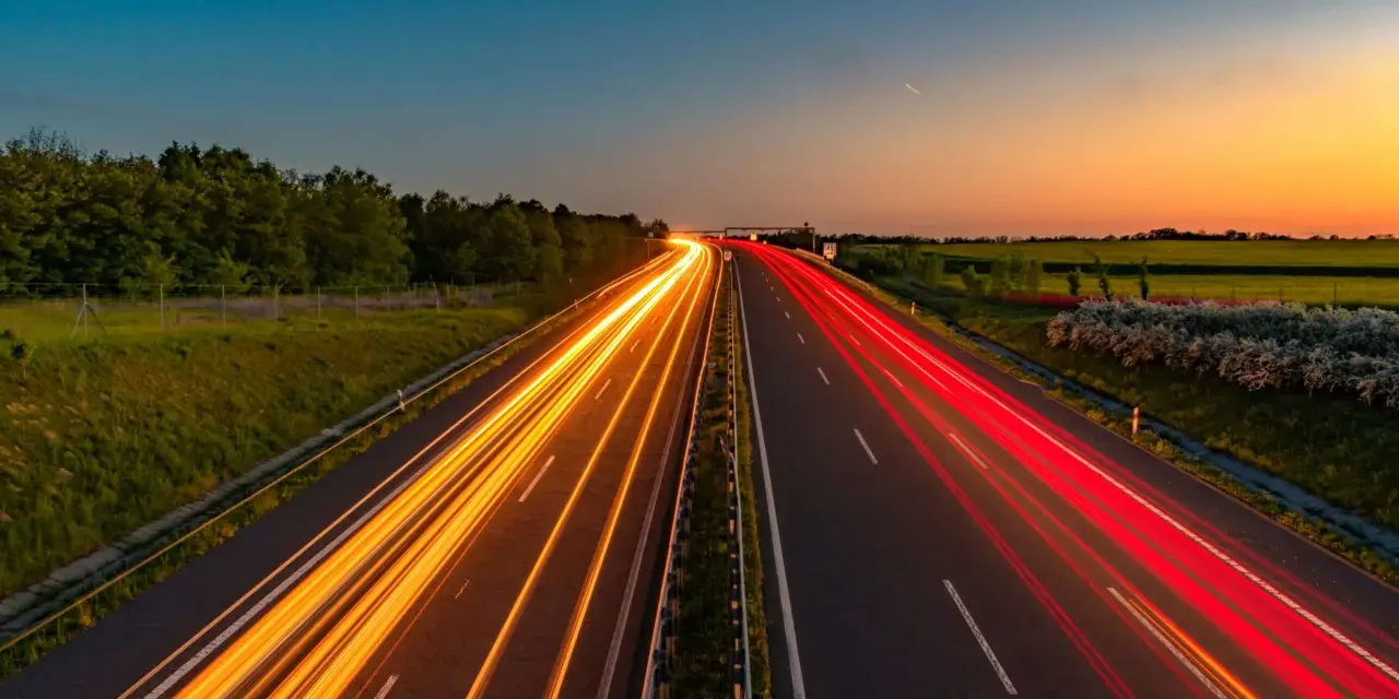 Ljusspår av bilar på en tysk autobahn vid solnedgången.