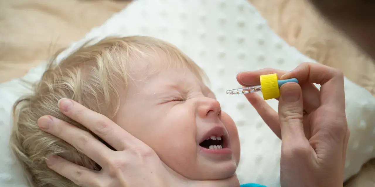 Ein Baby weint, während ihm N सेंटropfen verabreicht werden.