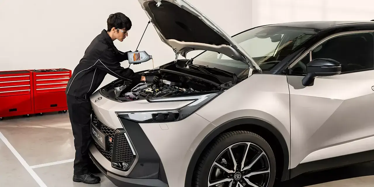 Mekaniker fyller på olja i en Toyota C-HR. För bästa service och pris på din Toyota Yaris, besök oss.