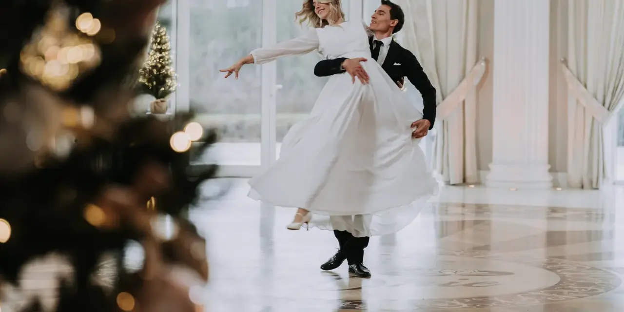 Para pierwszy taniec bez stresu, kursy online czy szkoła tańca? Młoda para w eleganckich strojach wiruje na parkiecie, tworząc romantyczną atmosferę.