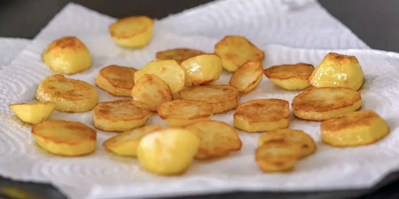 Patatas al horno doradas y crujientes, recién salidas del horno y reposando sobre papel absorbente. ¡Un manjar listo para disfrutar!