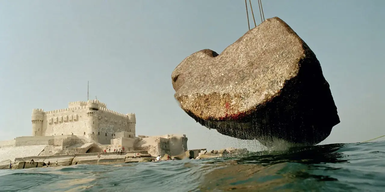 Un bloc de pierre, vestige du phare d'Alexandrie, est soulevé au-dessus des eaux, près de la citadelle de Qaitbay.
