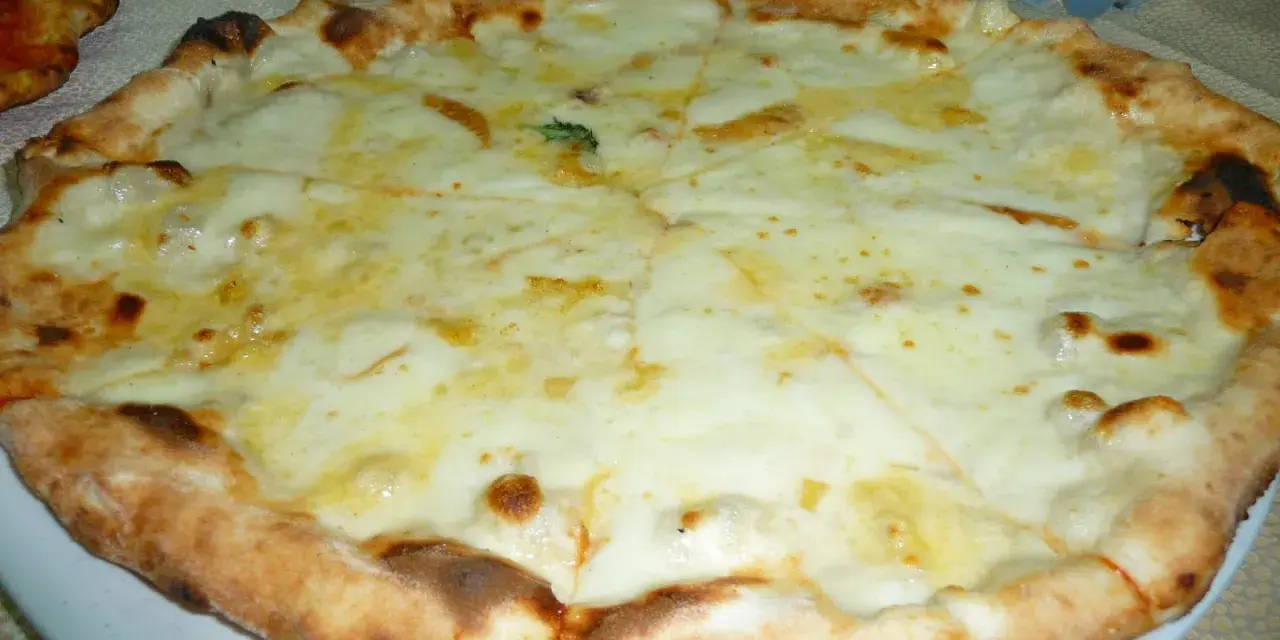 Pizza 4 formaggi appena sfornata, con crosta dorata e abbondante formaggio fuso.