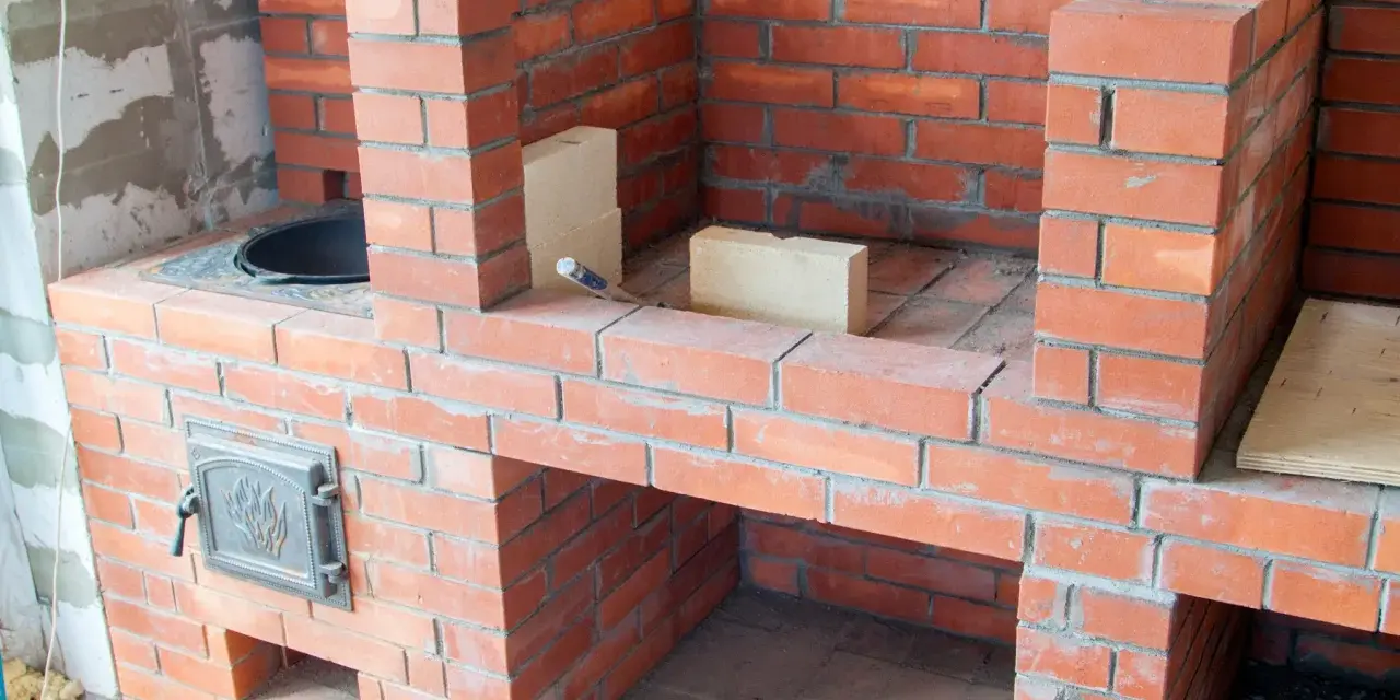 Construcción de chimeneas de obra de leña. Ladrillos rojos y mortero gris forman una estructura robusta, lista para encender el fuego.