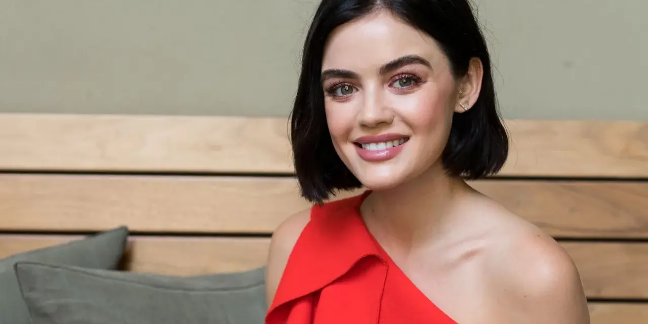 Lucy Hale sorride con un vestito rosso, ricordando i suoi film e programmi TV.