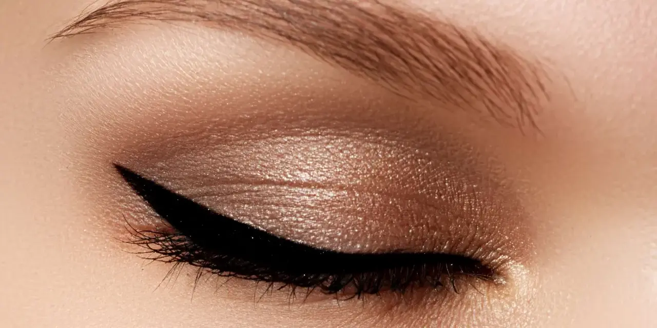 Occhio con trucco cat eyes, eyeliner nero definito e ombretto bronzo scintillante. Sopracciglio curato.
