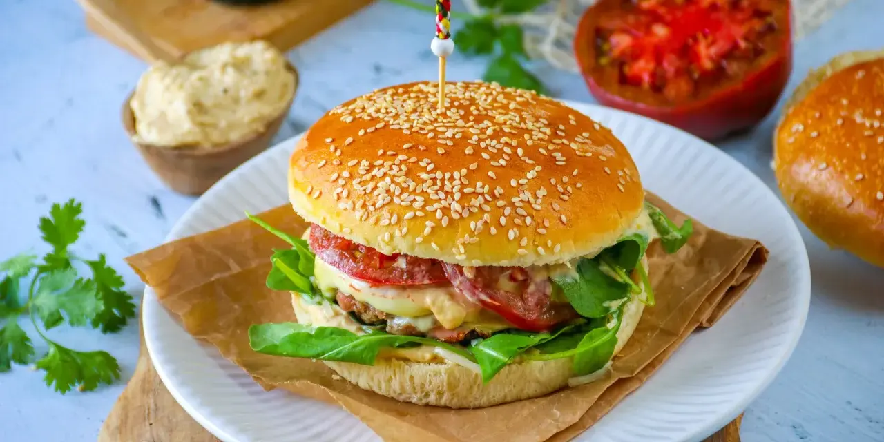 Un délicieux pain burger maison garni de légumes frais, de fromage fondant et d'une viande savoureuse. Un régal pour les yeux et les papilles !
