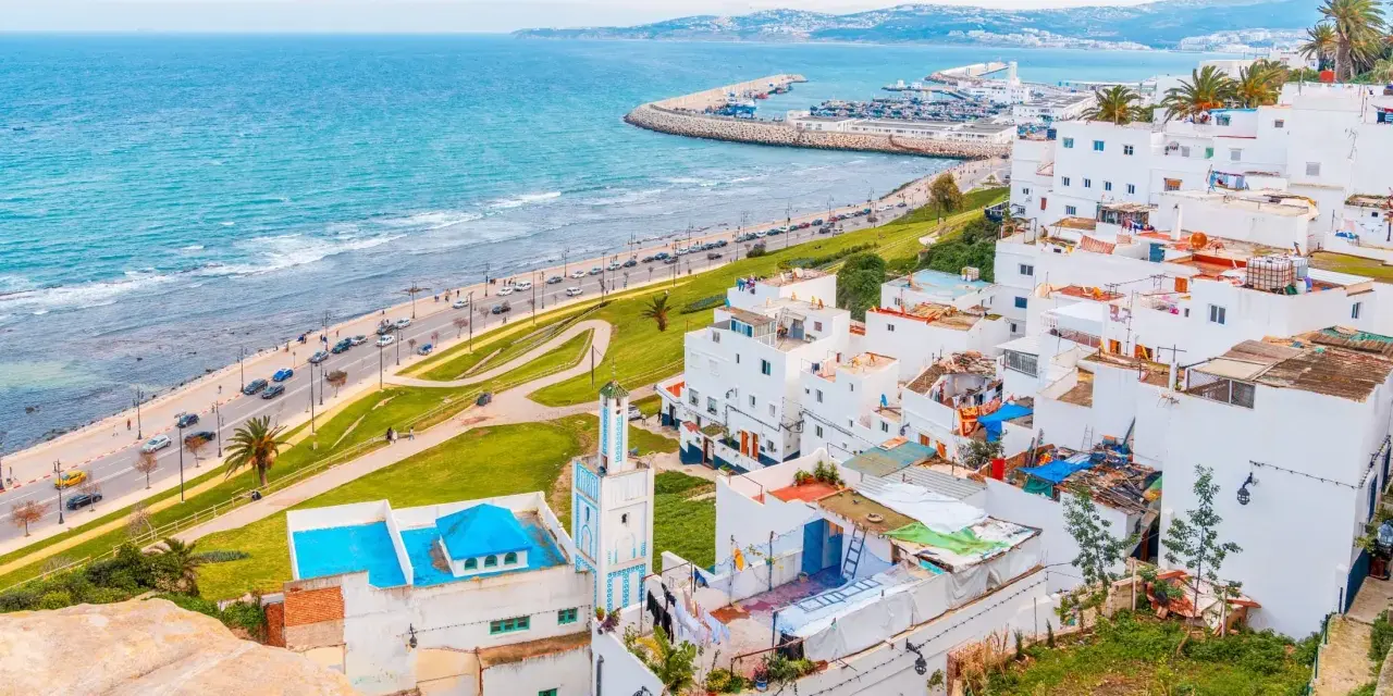 Widok na białe miasteczko z meczetem i turkusowym morzem, w oddali widać port. Tarifa Tanger prom.