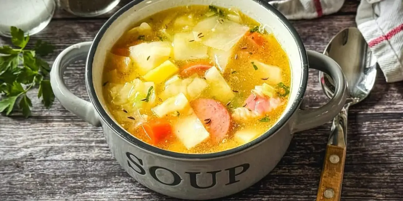 Herzhaftes Kohlsuppe Rezept mit Kartoffeln und Wurst in einer grauen Schüssel, bereit zum Genießen.