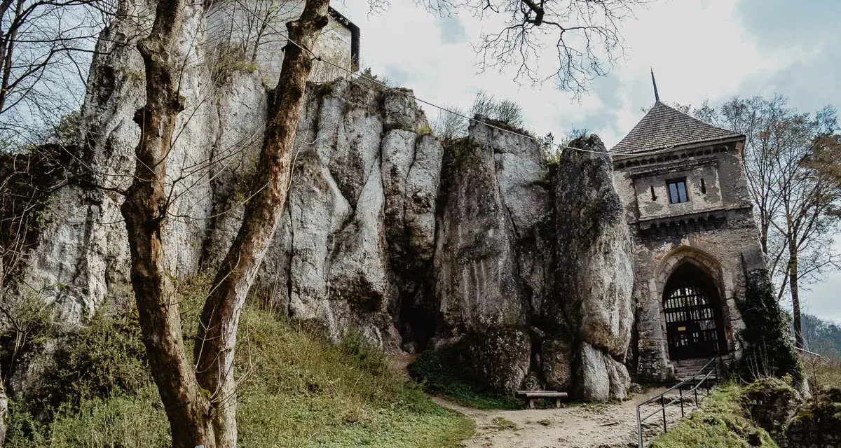 Ojcowski Park Narodowy atrakcje: ruiny zamku na skale, kamienna wieża bramna i ścieżka wśród zieleni.