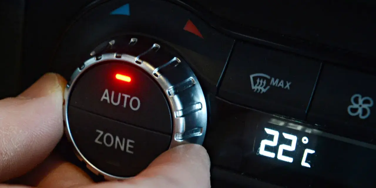 Hand dreht am Regler der **Klimaanlage Auto** auf 22 Grad Celsius. Rote LED leuchtet.