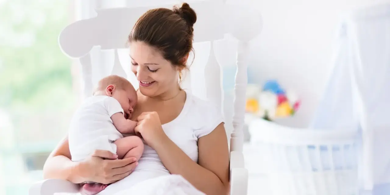 Uśmiechnięta mama kołysze śpiące dziecko. Gratulacje z okazji narodzin dziecka!