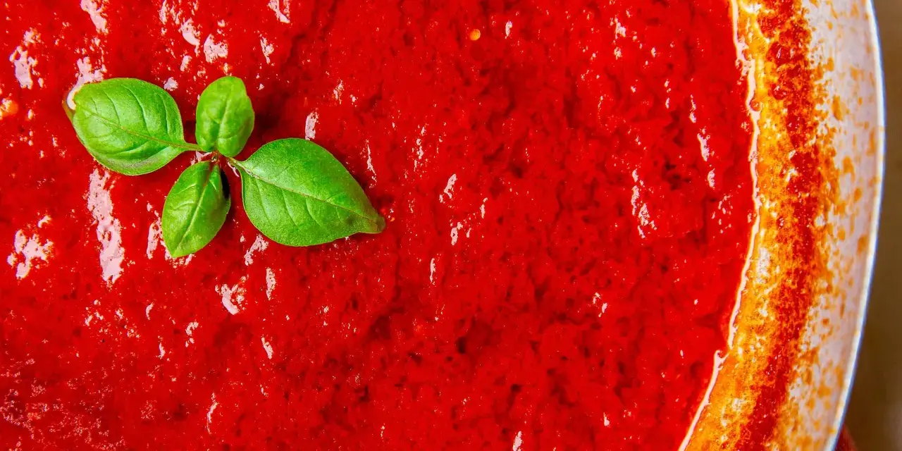 Leuchtend roter Sugo di Pomodoro mit frischen Basilikumblättern, bereit für Pasta.