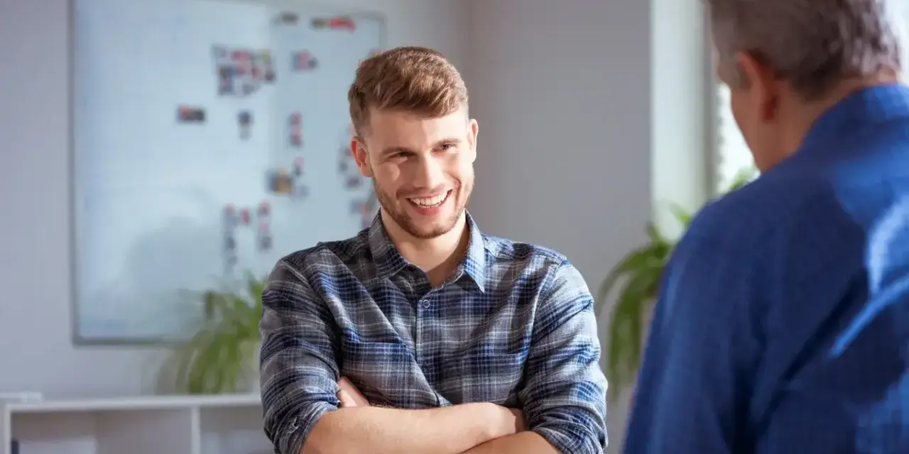 Uśmiechnięty młody mężczyzna w kratę rozmawia z starszym panem. Może to być rozmowa o pracy, gdzie młody człowiek szuka wsparcia od swojego sponsor aa.