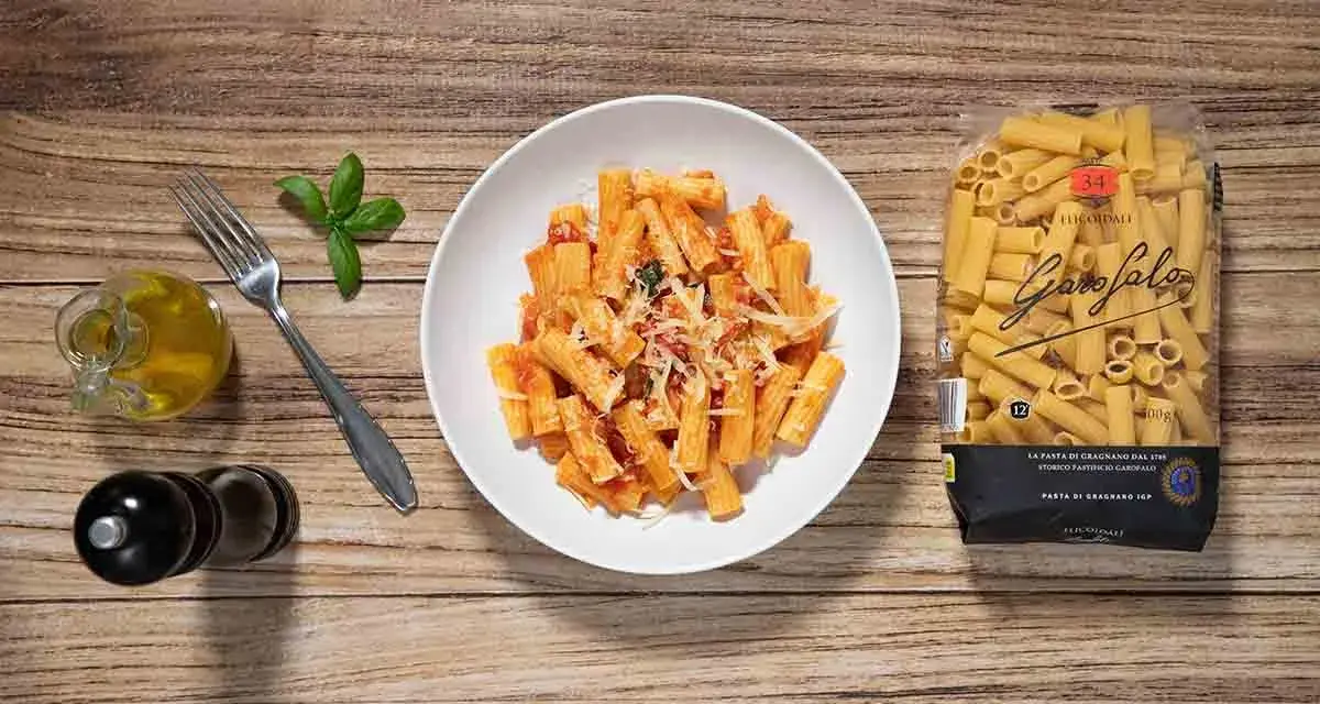 Macarrones a la napolitana servidos en un plato blanco, con un paquete de pasta Garofalo al lado.