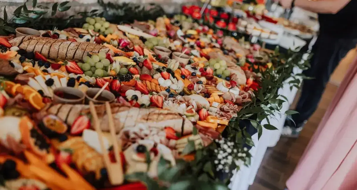 Stół pełen smakołyków na poprawiny: sery, wędliny, owoce, pieczywo i dipy. Idealna uczta po weselu.