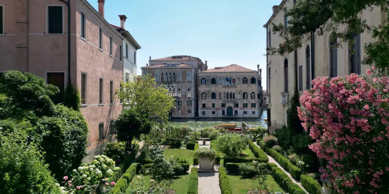 Giardini segreti a Venezia, con un canale e palazzi storici sullo sfondo. Un'oasi di pace tra il verde e i fiori.