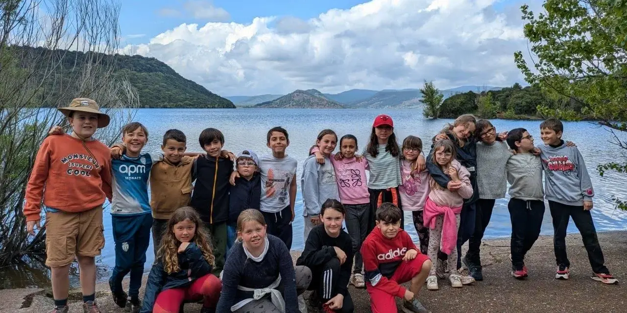 Un animateur pour combien de jeunes ? Un groupe d'enfants souriants pose devant un lac, prêts pour l'aventure.