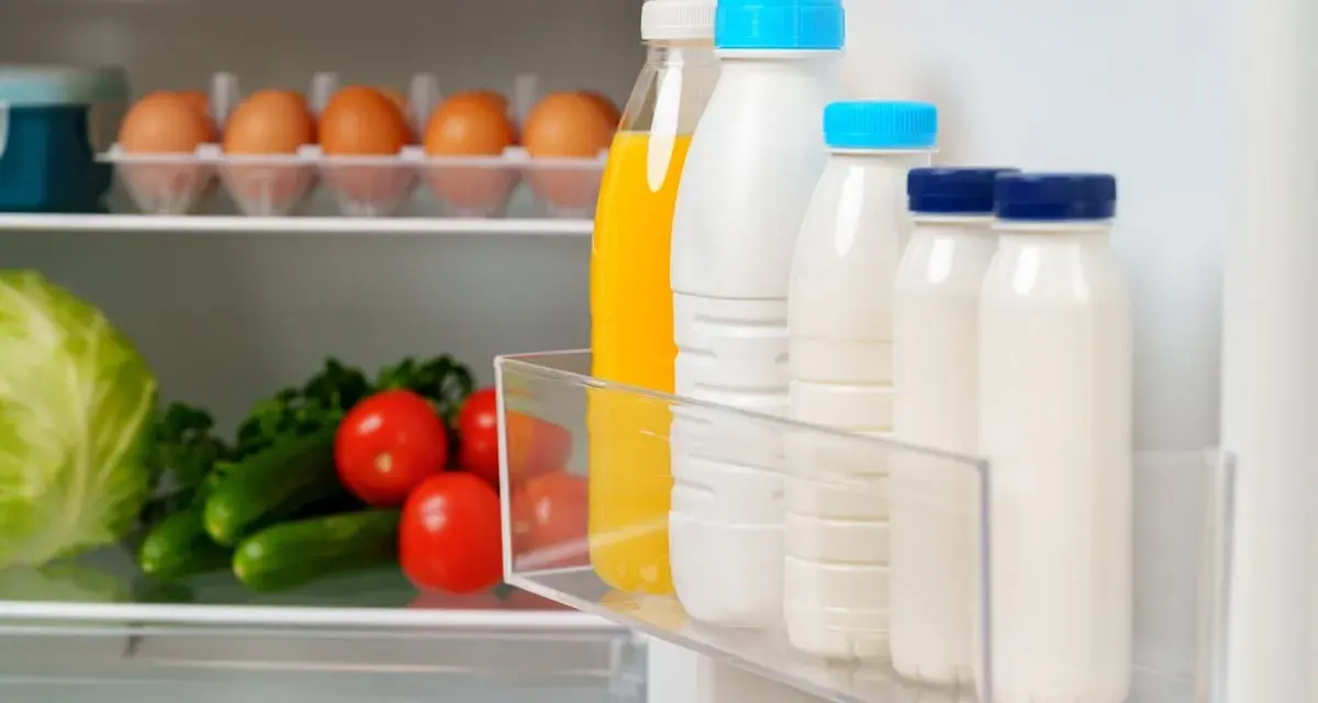 Bouteilles de lait et jus pour une bonne conservation lait frigo. Légumes frais sur l'étagère du bas.