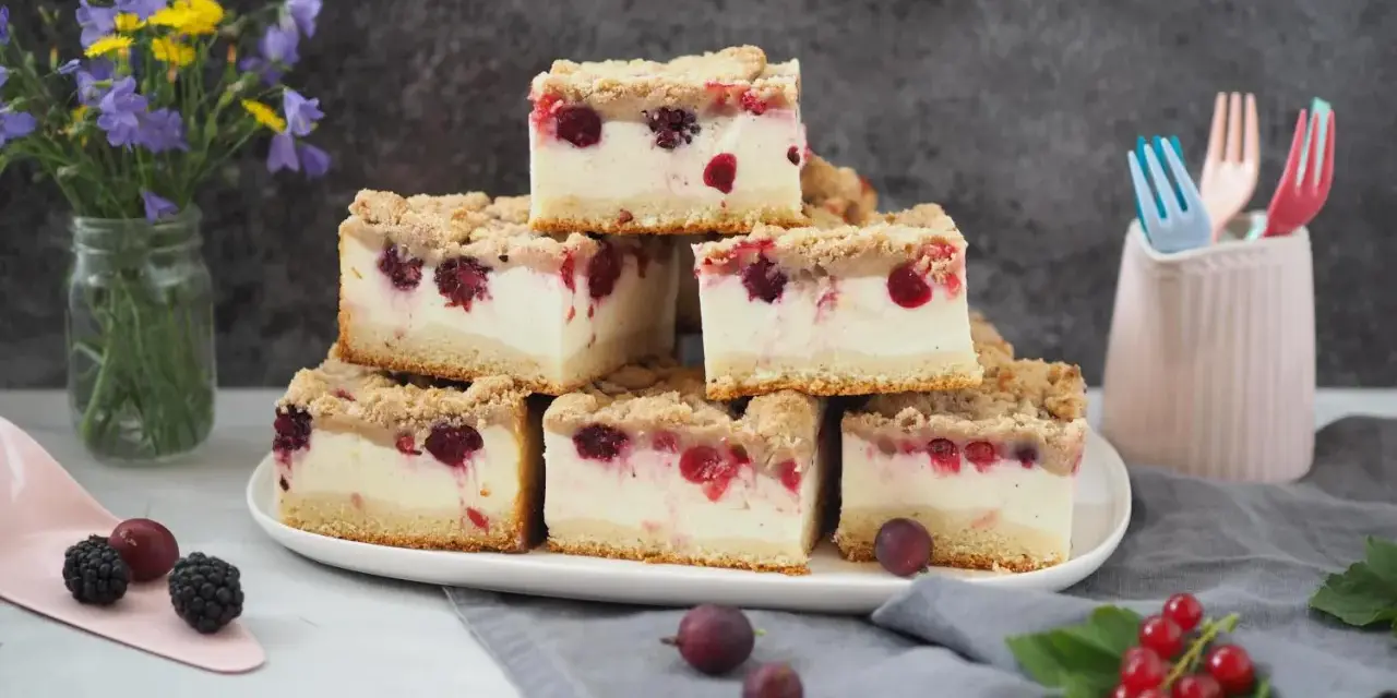 Stapel von saftigen Kuchenstücken mit Beeren und Streuseln – ein erfrischender Sommerkuchen, der Lust auf mehr macht.