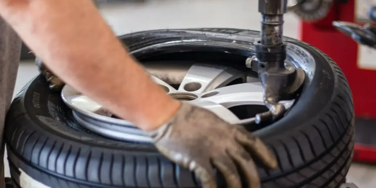 Un meccanico lavora su una gomma. La domanda su ogni quanti km si cambiano le gomme è importante per la sicurezza.