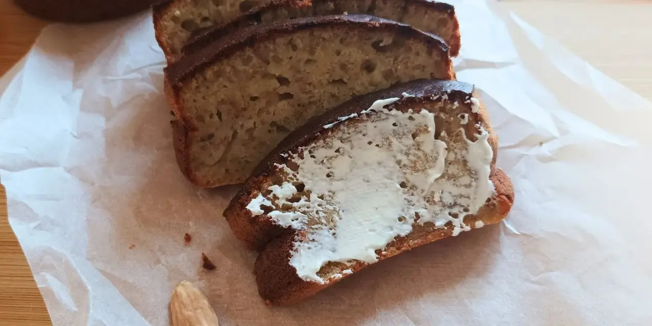 Pyszny chlebek bananowy z airfryera, pokrojony w kromki, jedna posmarowana masłem. Idealny na śniadanie.