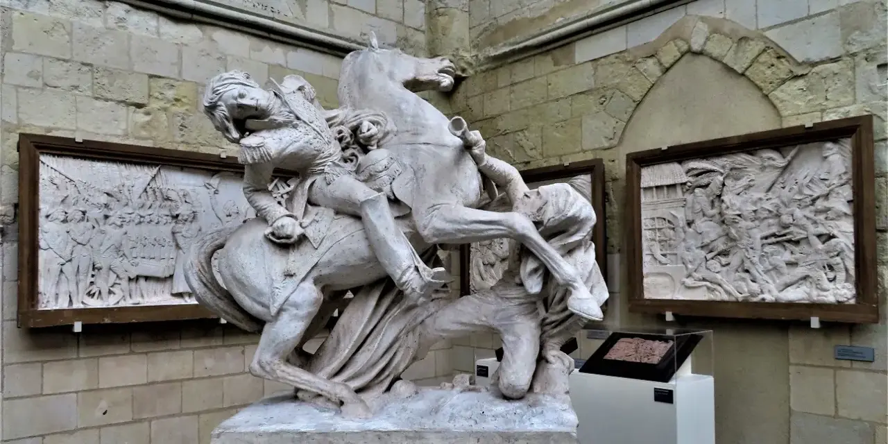 Sculpture équestre de David d'Angers, un homme en uniforme militaire sur un cheval cabré, avec des bas-reliefs en arrière-plan.