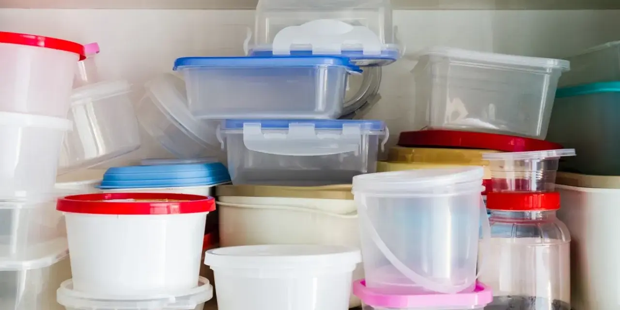 Stos pojemników na żywność, niektóre z kolorowymi pokrywkami. Uważaj na ftalany w plastiku.