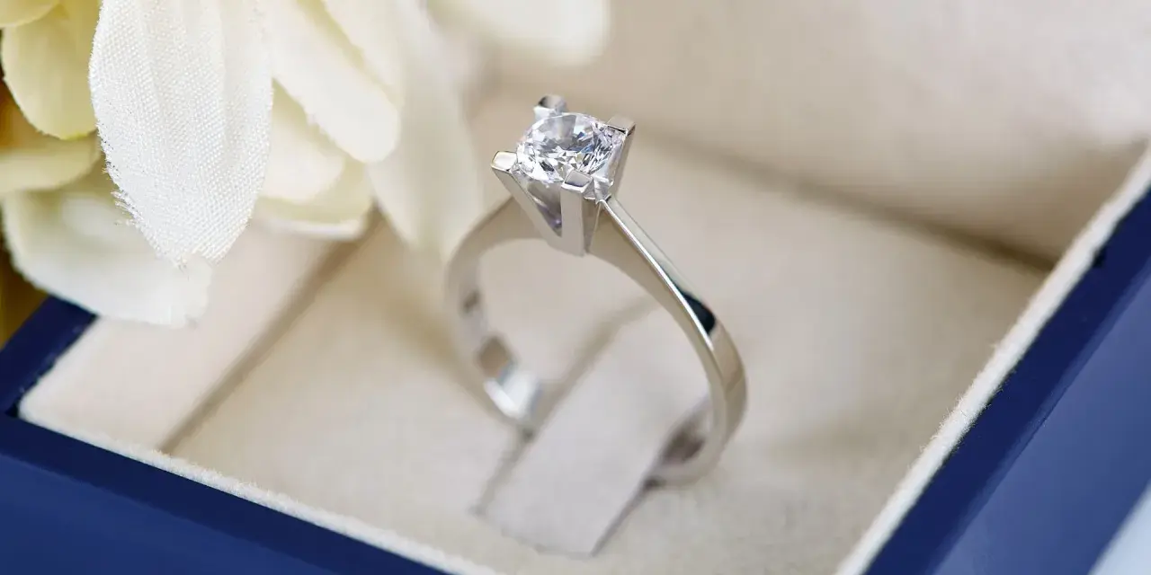 Anello con diamante in un cofanetto blu. La brillantezza del diamante, misurata in carati, cattura la luce.