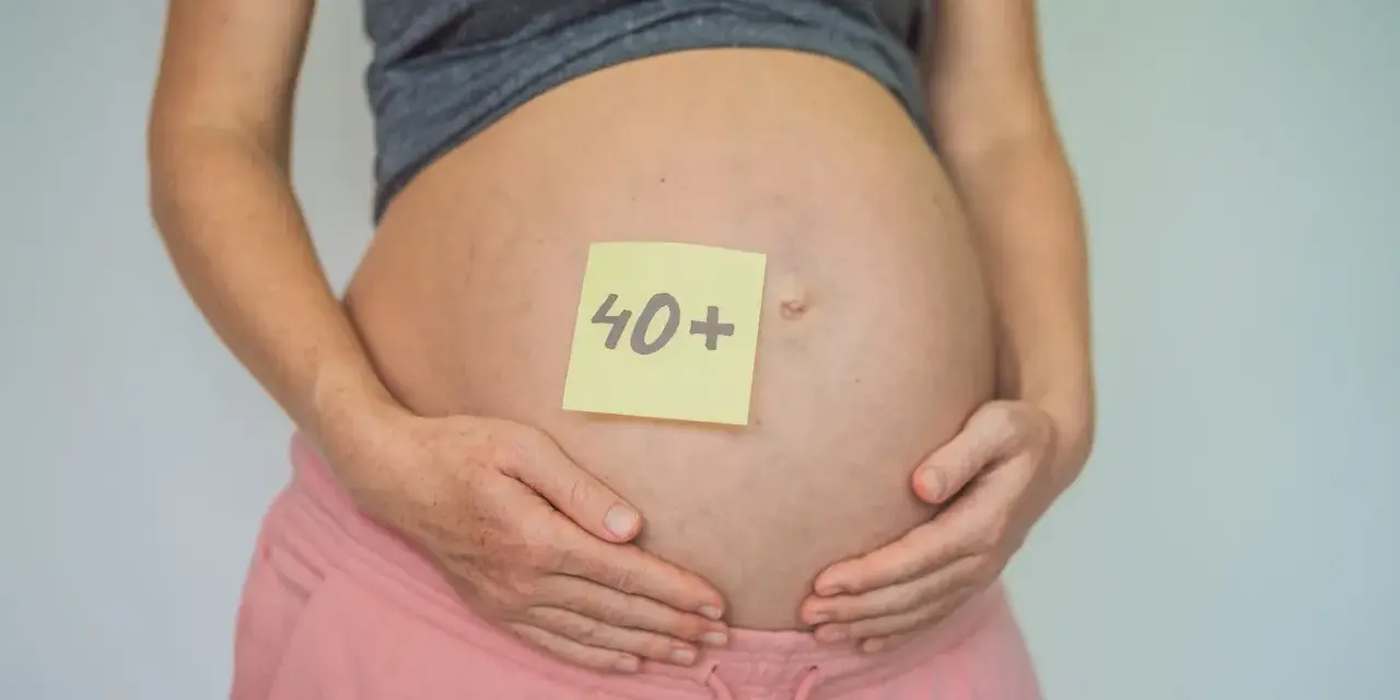 Brzuch kobiety w ciąży z karteczką "40+". To dowód, że ciąża po 40. jest możliwa i piękna.