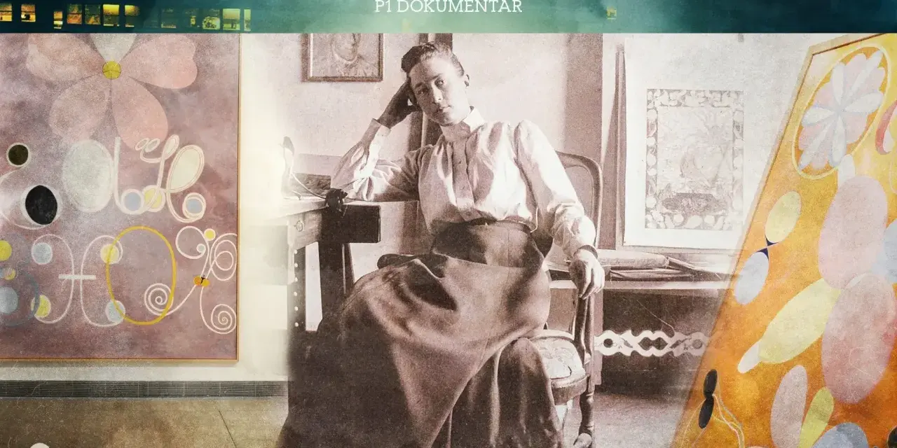 Hilma af Klint barn, en ung kvinna i en vit blus och mörk kjol, sitter vid ett bord omgiven av sina abstrakta målningar.