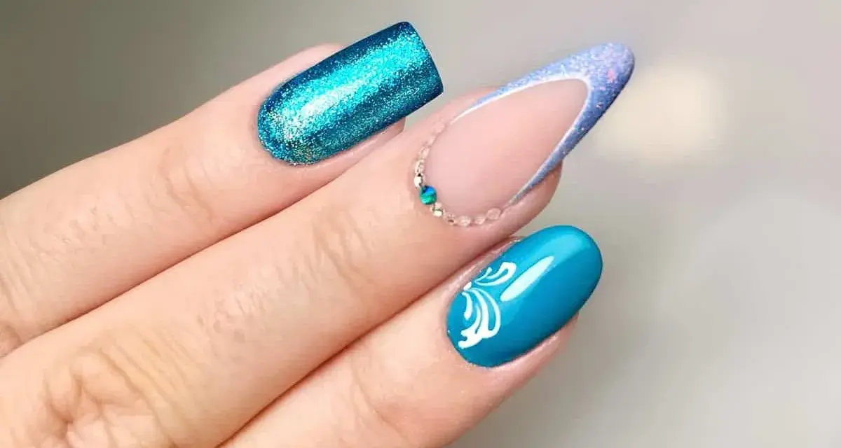Unghie con glitter blu elettrico, french manicure con glitter azzurro e decorazioni floreali bianche. Nuove forme unghie che ispirano.