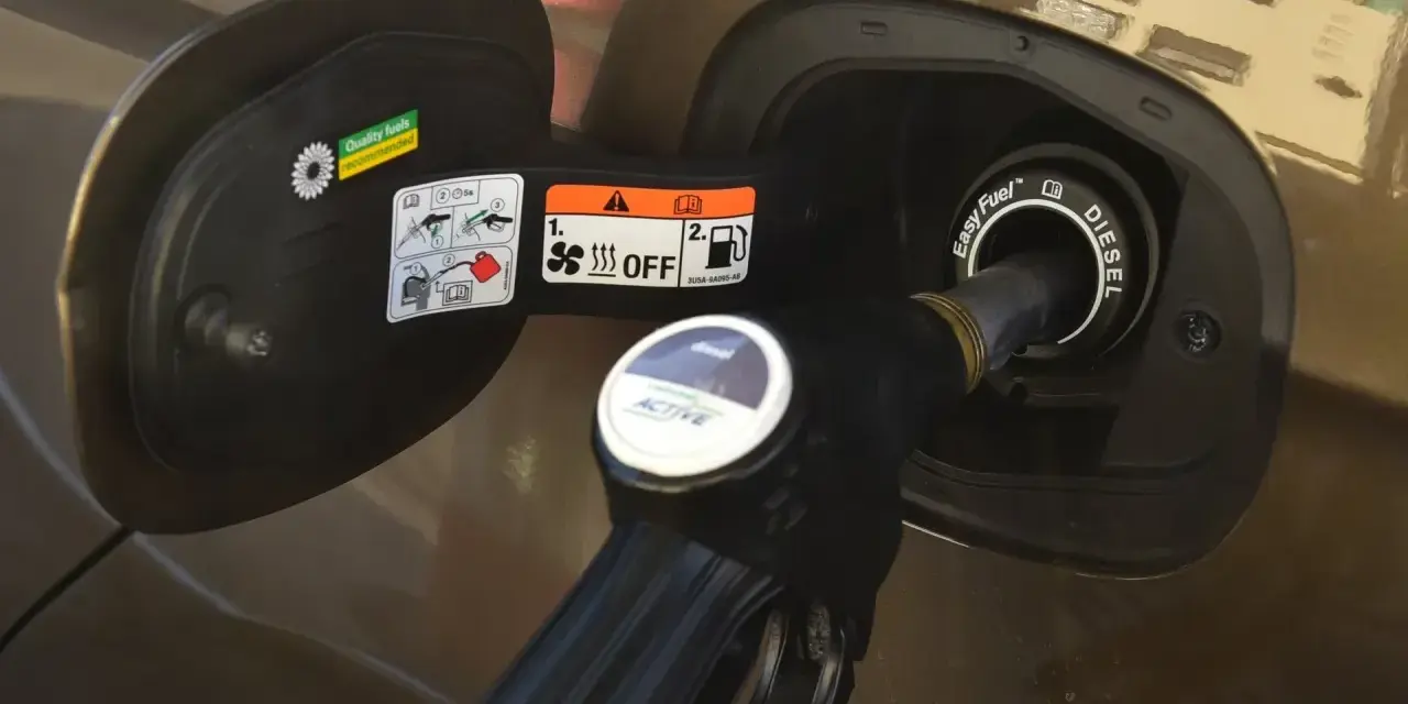 Dozbrań do baku diesla. Pistolet paliwowy wlewa paliwo do samochodu, pokazując, jak zatankować auto.