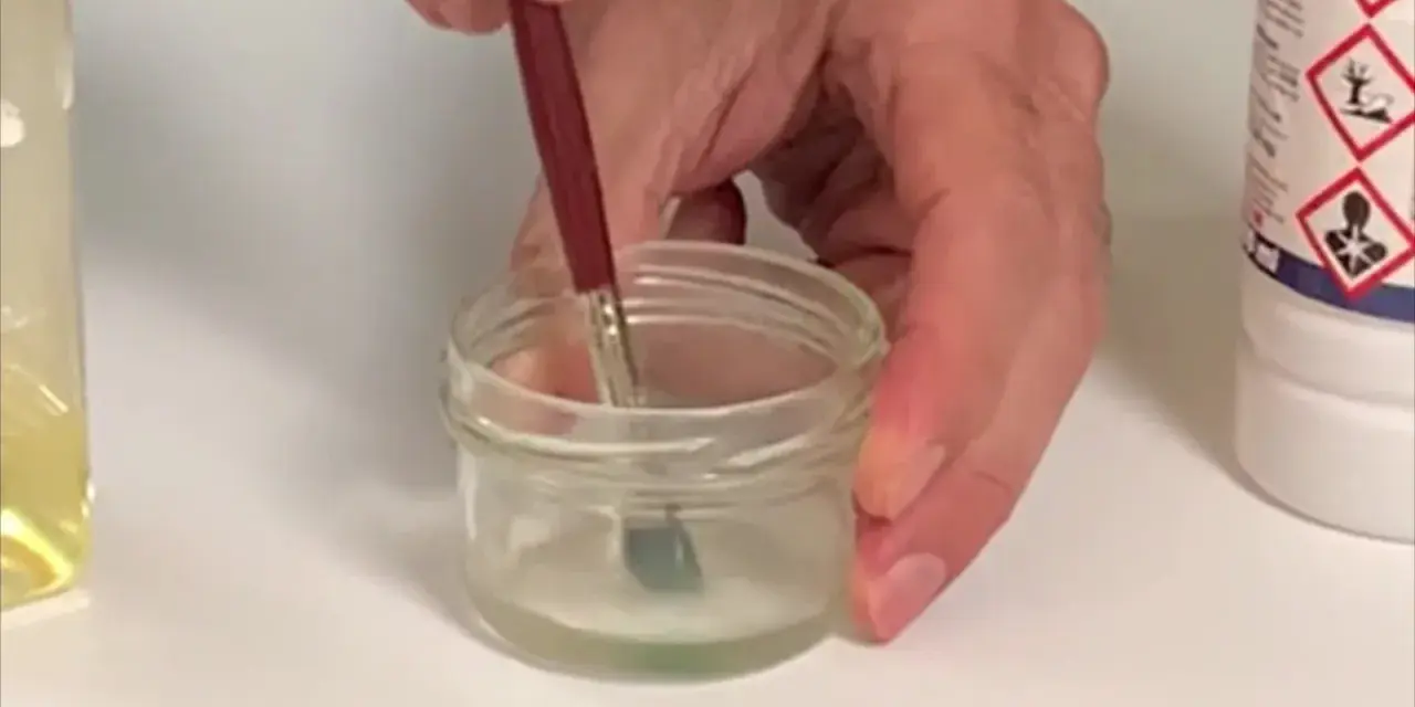 Pincel sumergido en un frasco con disolvente oleo, listo para limpiar.