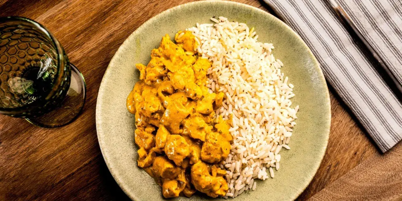 Plato de arroz con pollo en salsa curry, acompañado de arroz blanco. Un delicioso arroz con verduras y proteína.