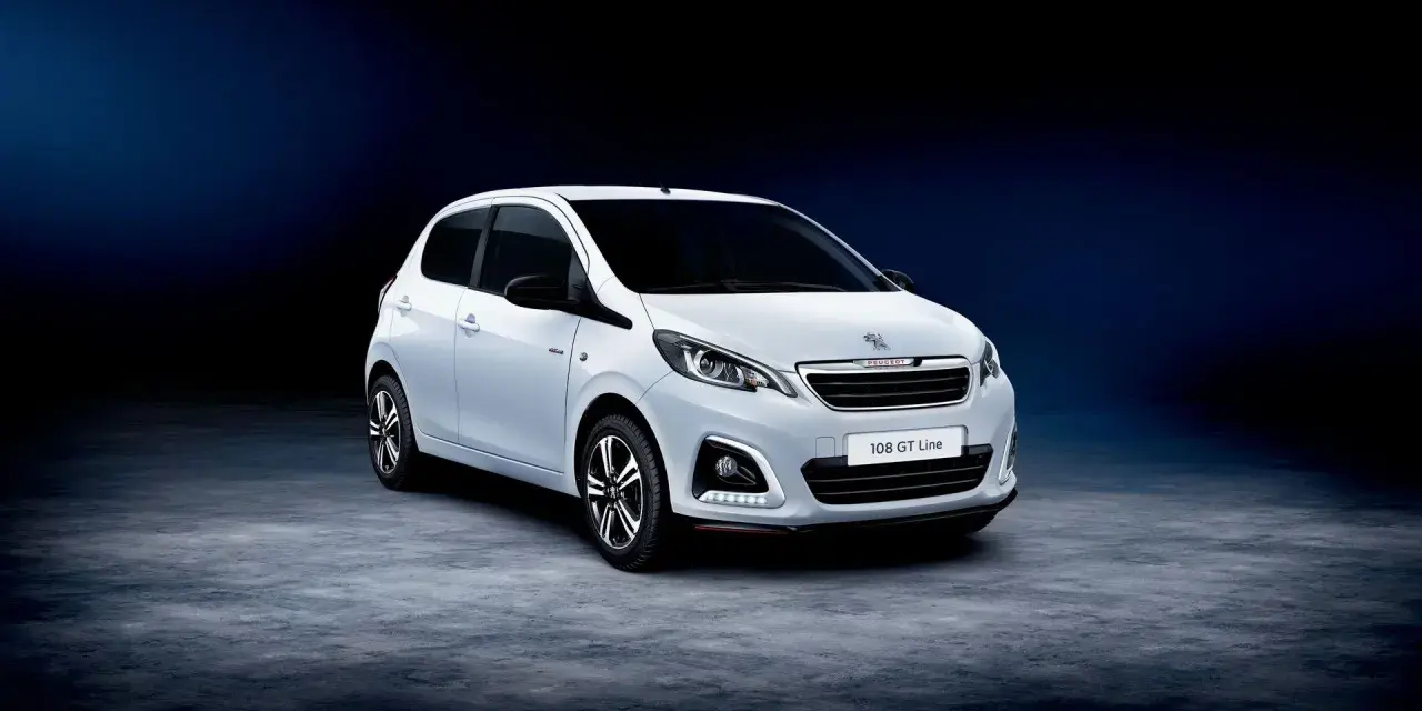Biały Peugeot 108 GT Line stoi na ciemnym tle.