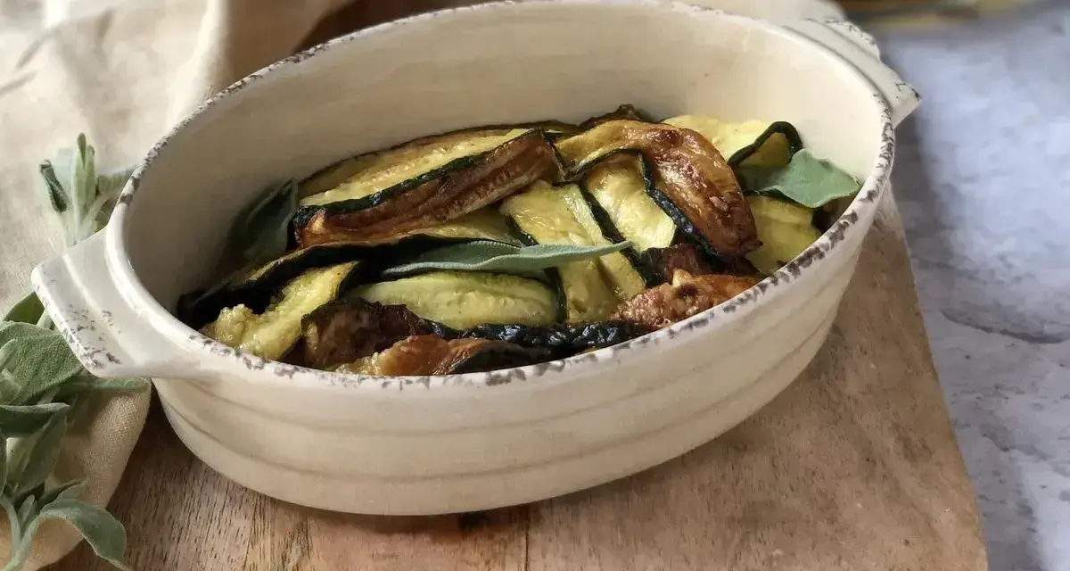Zucchine in carpione dorate e saporite, guarnite con foglie di salvia fresca, servite in una ciotola rustica.
