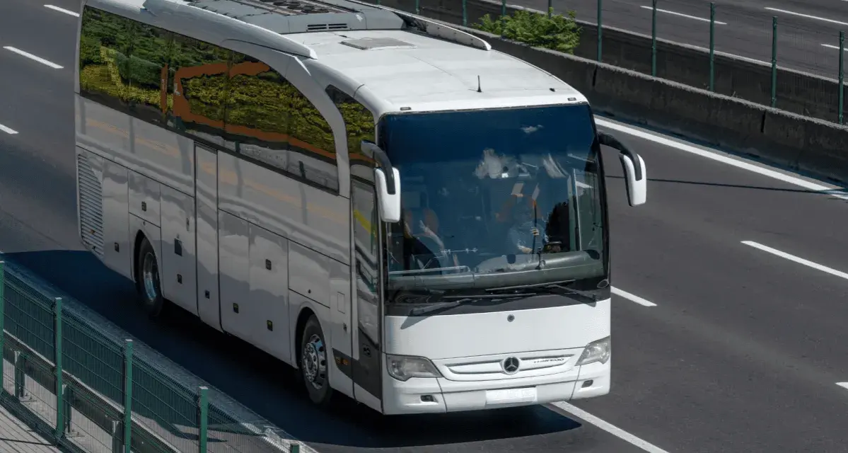 Biały autokar jedzie autostradą. Zastanawiasz się, ile pali bus na 100 km?