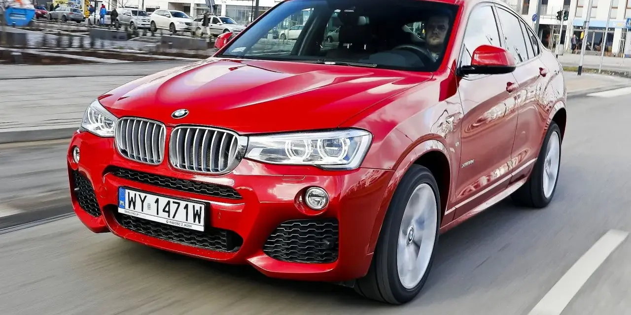 Czerwone BMW X4 w ruchu miejskim. Wady tego modelu mogą dotyczyć widoczności z tyłu i ograniczonej przestrzeni bagażowej.