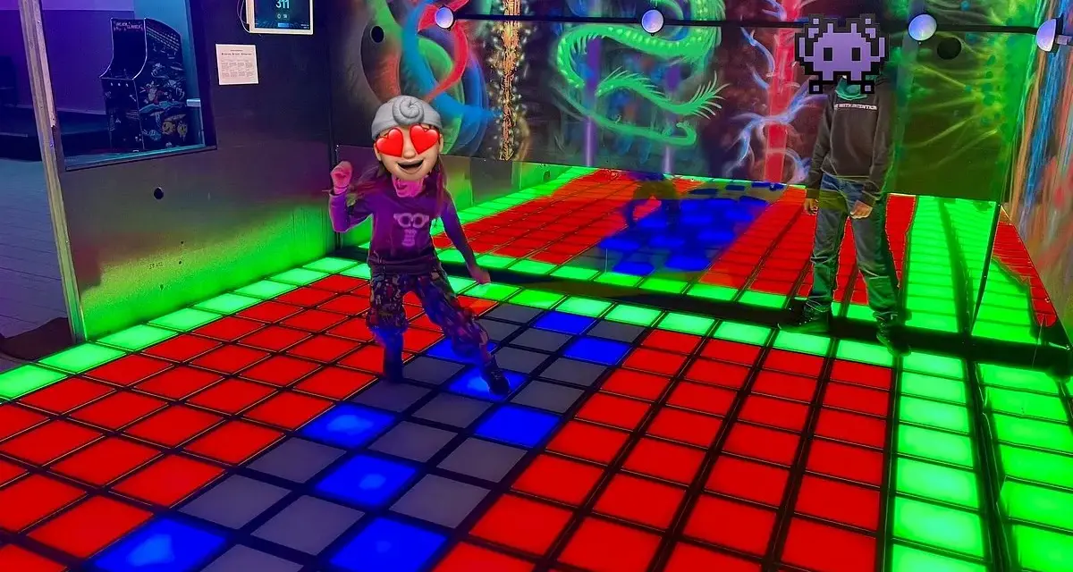 Kinder spielen im **underground lasergame Berlin** auf einer leuchtenden Tanzfläche. Bunte Drachen zieren die Wand.