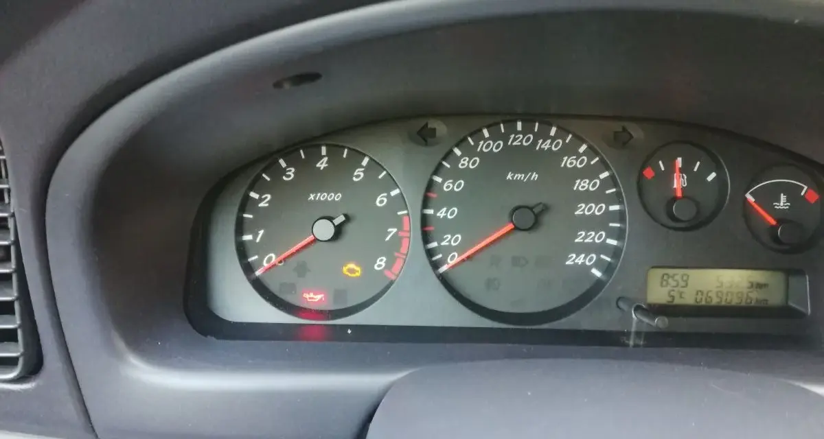 Migająca kontrolka samochodu z kluczykiem Nissan na desce rozdzielczej. Obok świeci się kontrolka oleju.