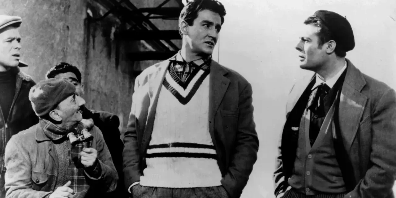 Uomini in abiti d'epoca, uno con un maglione a V, discutono animatamente. Un'iconica scena della commedia all'italiana.