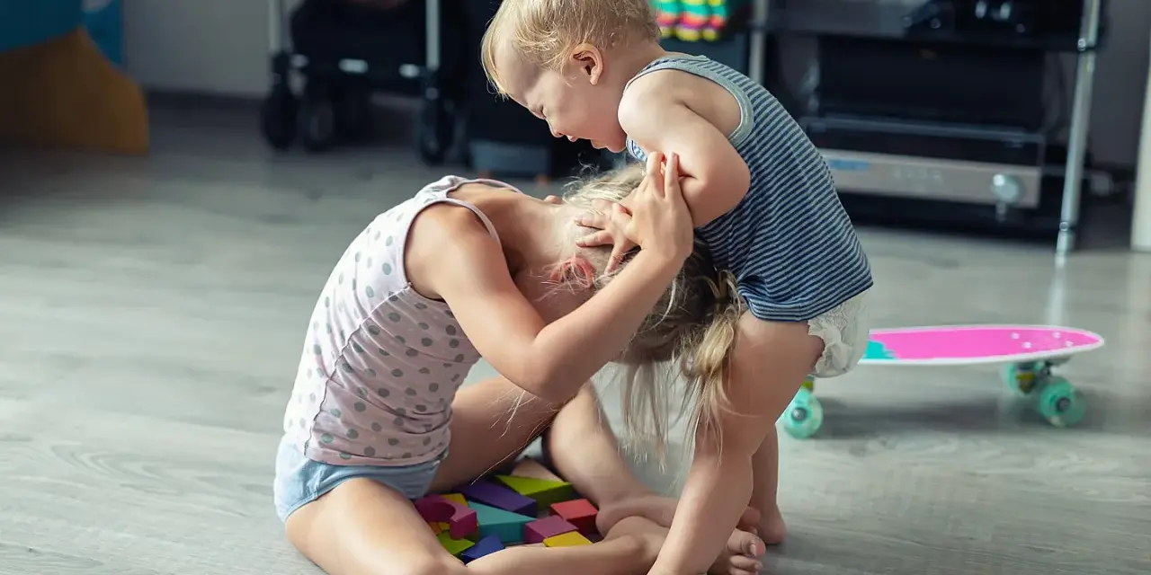 Kleinkind hält älteres Kind am Kopf fest. Was tun, wenn Kinder schlagen? Hier wird spielerisch gestritten.