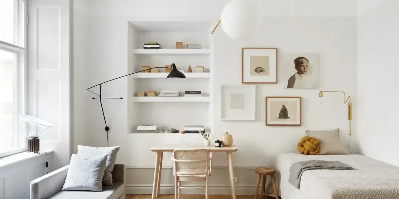 Accogliente camera da letto minimal con letto singolo, scrivania in legno, divanetto e quadri alle pareti.