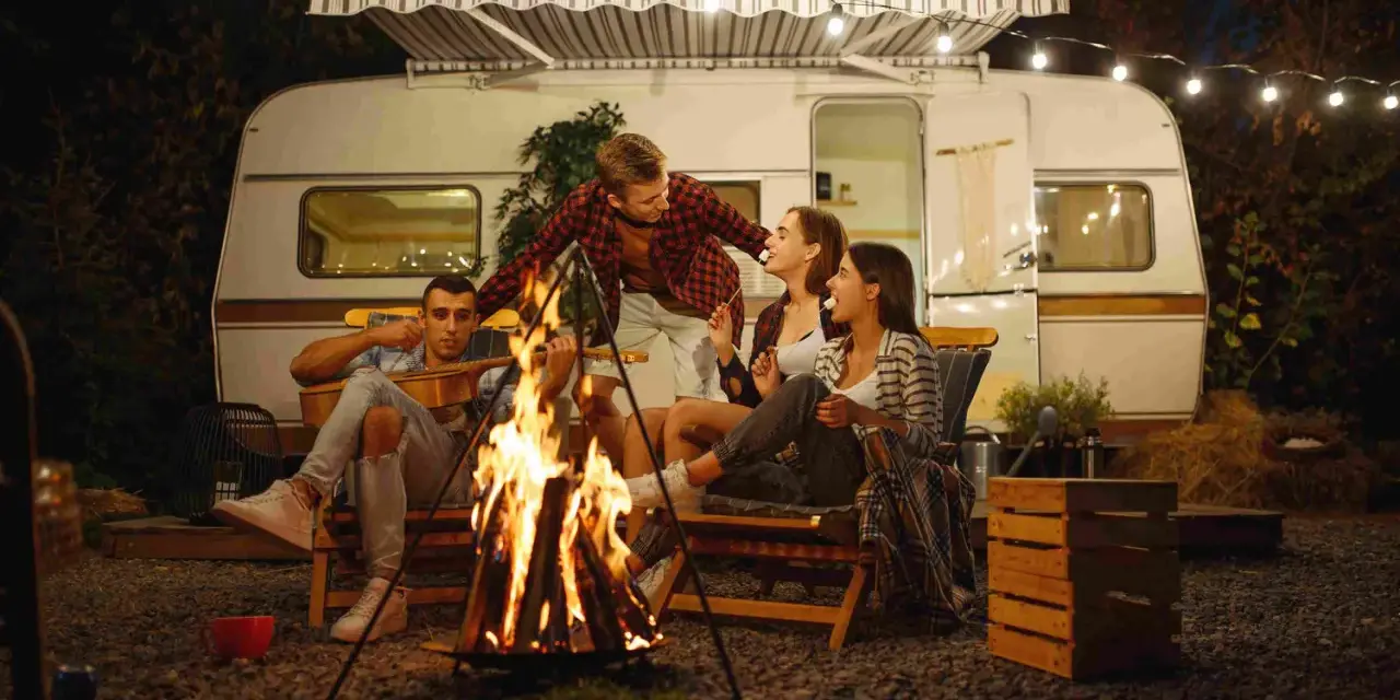 Freunde genießen einen gemütlichen Abend bei Lagerfeuer und Gitarrenmusik während ihres Campingurlaubs in Deutschland.