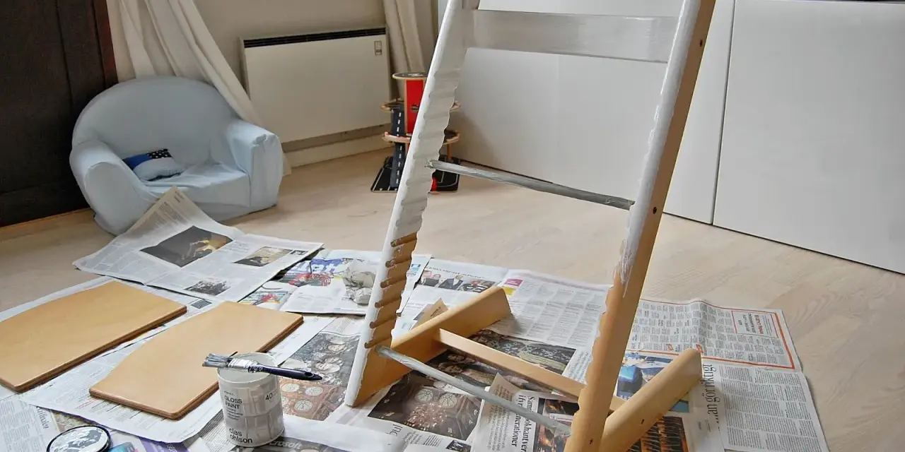 Måla om Stokke stol med vit färg. Trädelar och pensel ligger på tidningspapper.