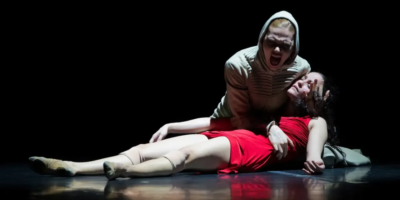 Una escena dramática de "Romeo y Julieta resumen corto": una mujer con capucha grita sobre otra, vestida de rojo, que yace en el suelo.