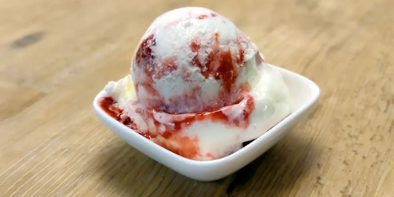 Ein Eisbecher mit Erdbeersoße, der zum sofortigen Genuss einlädt. Ein wahrer "Ed von Schleck" Moment!