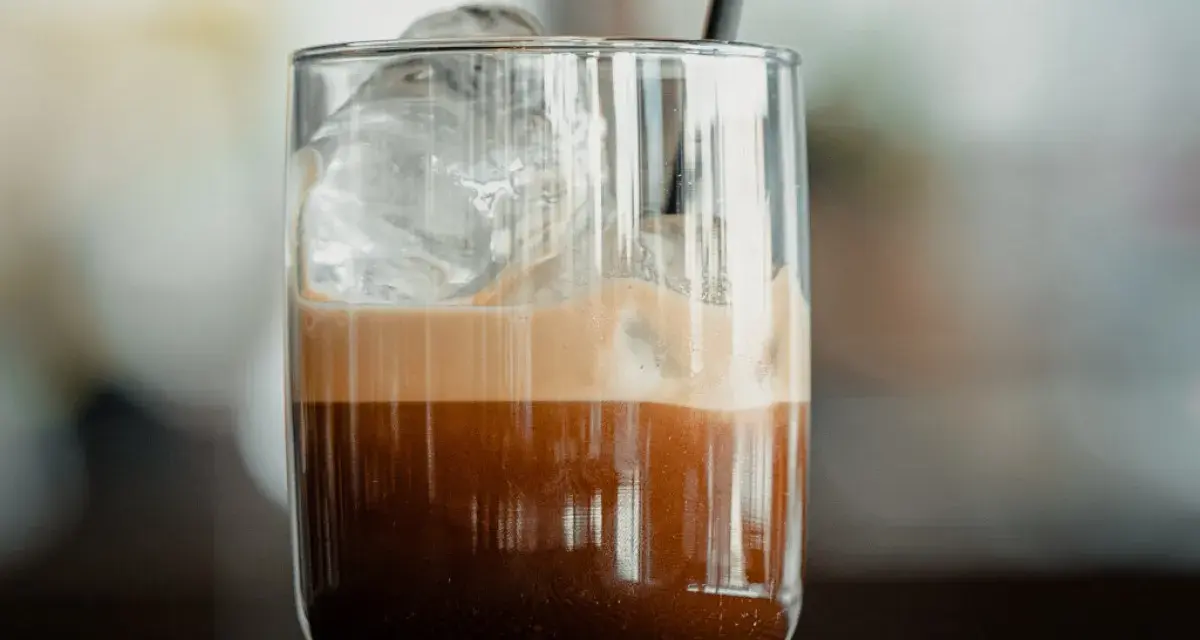 Orzeźwiające freddo espresso z lodem i pianką w szklance, gotowe do wypicia.