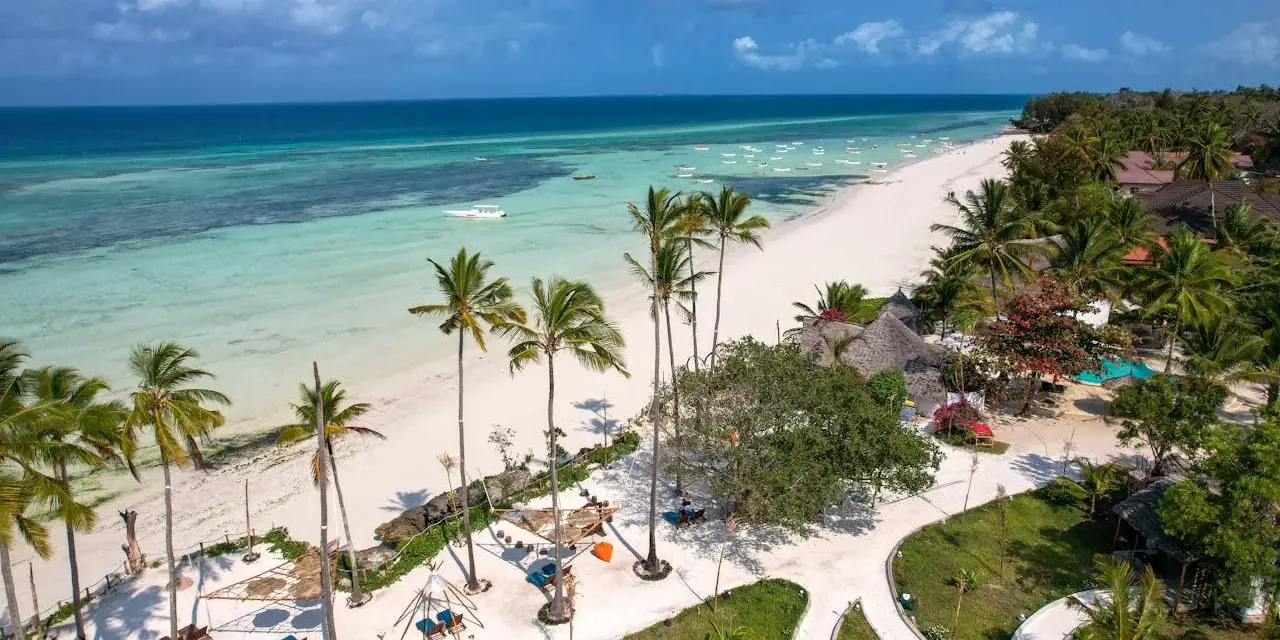 Rajska plaża na Zanzibarze, z turkusową wodą i palmami. Nawet podczas pory deszczowej Zanzibar zachwyca pięknem.